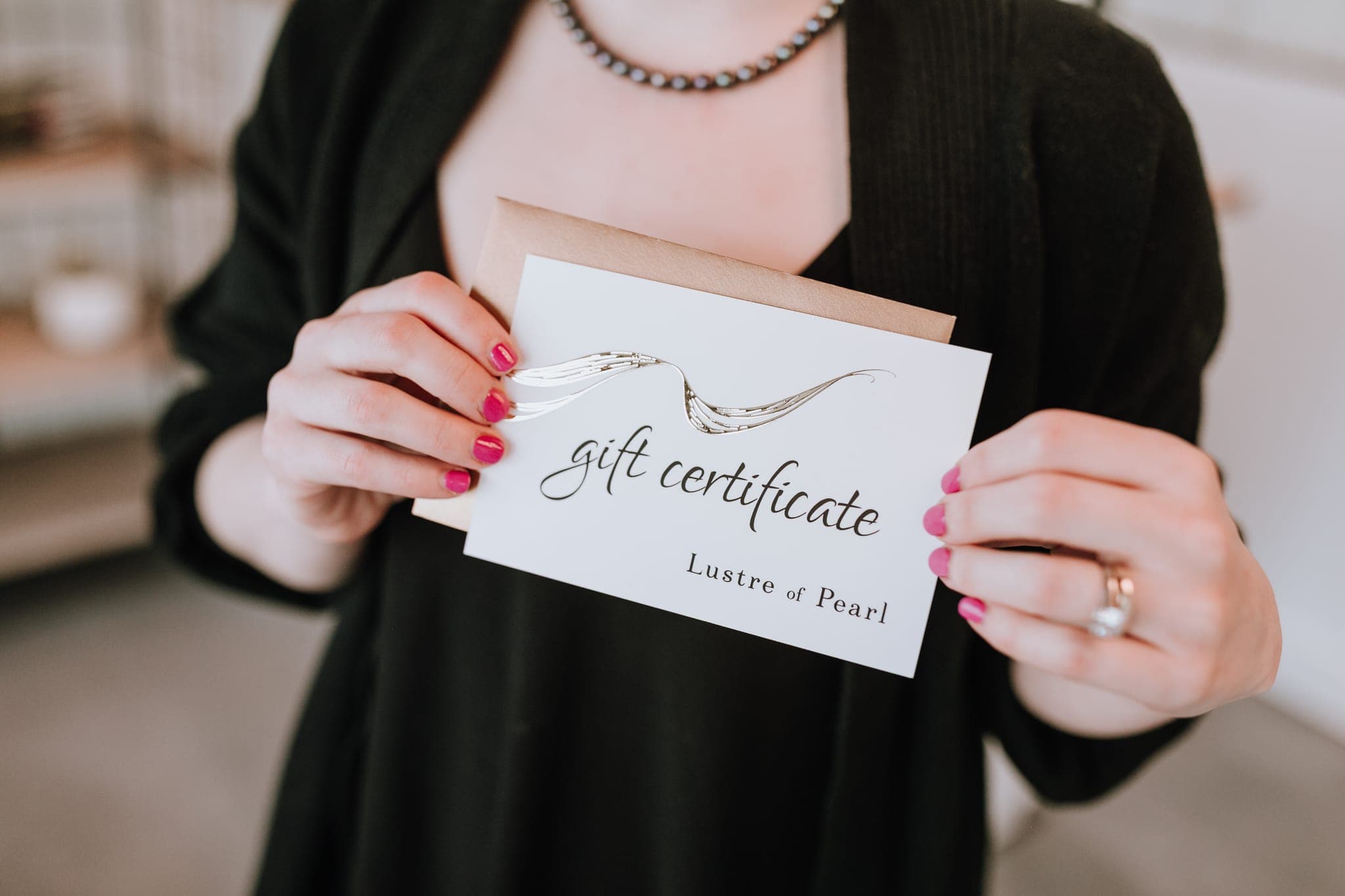 A Lustre of Pearl gift certificate held in two hands